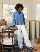 Load image into Gallery viewer, Woman standing in a home interior wearing a blue shirt and white pants.