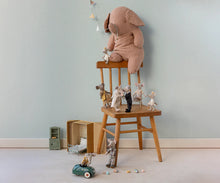 Load image into Gallery viewer, Pink elephant toy on a wooden stool with small figurines in a room with light blue walls.