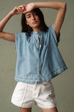 Load image into Gallery viewer, Woman wearing a light blue denim shirt and white shorts against a neutral background